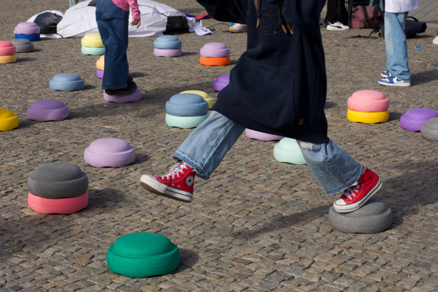 Ein Kind springt zwischen bunten Stapelsteinen auf dem Pariser Platz